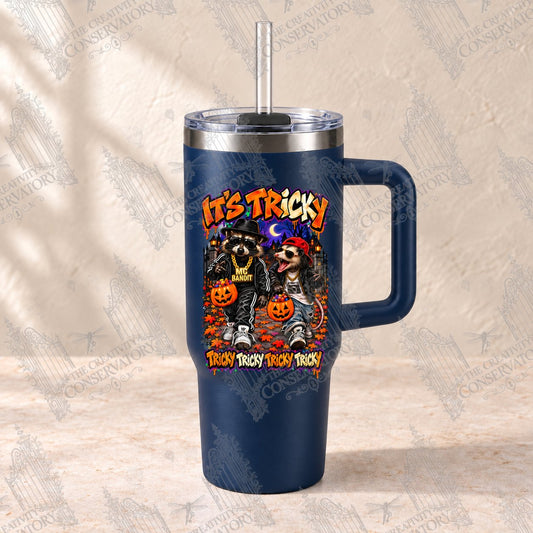 It’s Tricky—MC Bandit and Beastie Possum on a navy 30-ounce Big Swig handled tumbler with clear reusable straw; repeating Wondergate watermark across the full photograph
